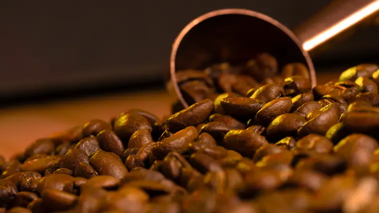 Coffee beans spilling from a copper spoon
