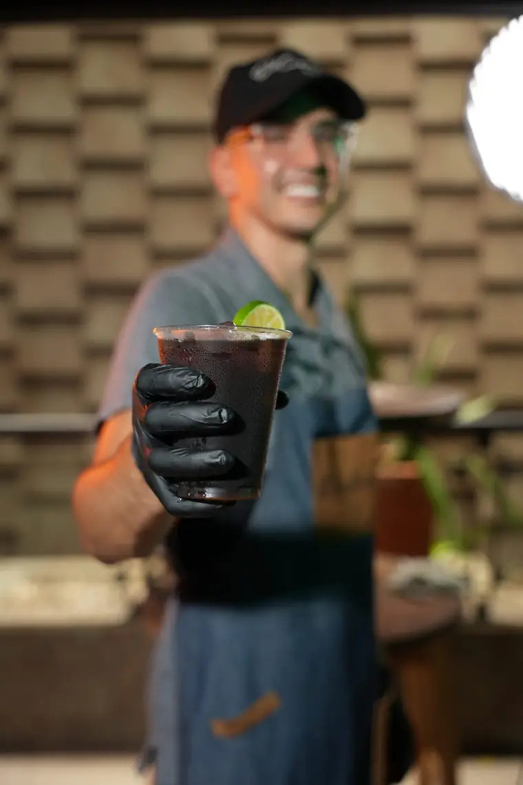 Barista serving a cold drink with lemon